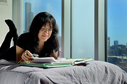 Photo of a student reading on her bed